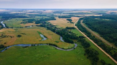 Yeşil tarladaki kıvrımlı nehrin havadan manzarası, insansız hava aracının güzel doğa arka planının üst görüntüsü. Kopya alanı olan mevsimlik yaz manzarası.