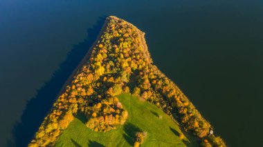 Sonbahar ormanı ve göl. Yukarıdan bak. Güneşli Sonbahar Gününde Göldeki Bir Adanın Hava Fotoğrafı. Doğa konsepti.