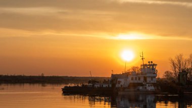 Dredger nehirdeki çim alanını derinleştirmeye çalışıyor. Nehirdeki bir tarakçı tarafından temizleniyor ve derinleşiyor. Nehirde gün batımı. Endüstriyel kavram.
