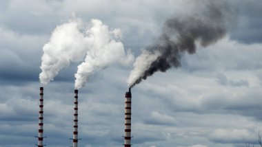 Gökyüzü arka planında bacadan çıkan endüstriyel duman. Kömür santralinden çıkan gri dumanlı yüksek baca borularının görüntüsü. Fosil yakıtlı elektrik üretimi. Rüzgâr kirliliği.