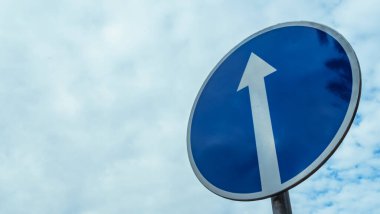 Bulutlu mavi gökyüzü arka planında trafik tabelası.