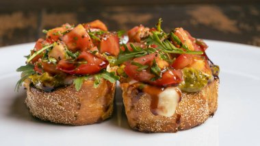 Domates ve mozzarella bruschetta 'nın yakın plan görüntüsü kırmızı tuğlalı arka planda beyaz tabakta..