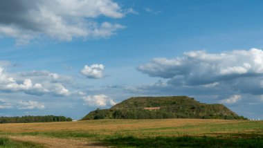 Kapalı şehir çöplüğü. Bölgenin restorasyonu. Büyük bir çöp yığınının peyzajı. Arka planda bir metropol ve bulutlu mavi bir gökyüzü var..