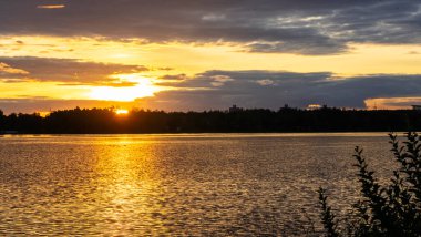 Göldeki şafak güneşinin ışınları. Nehirdeki günbatımı bulutlarının yansıması. Kırsal alan. Panoramik pankart. Panoramik pankart. Doğa konsepti.