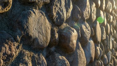 Gri ezilmiş taşlar ve güneş ışığıyla gerçek bir arka plan. Yaz günlerinde eski tuğla duvar. Soyut dekoratif arkaplan veya sanat dokusu.