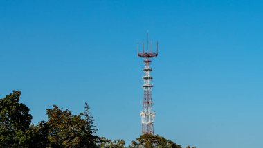 Mavi gökyüzü arka planında cep telefonu antenleri olan televizyon ve radyo kulesi..