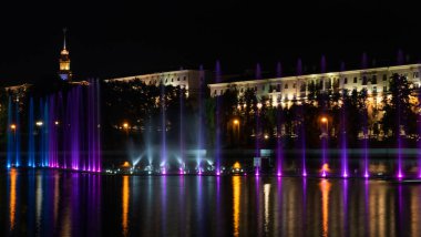 Geceleyin bir nehirde çok renkli bir müzik çeşmesi. Aydınlanmadan kaynaklanan gece çeşmesi. Mesaj için yer var. Kutlama konsepti.
