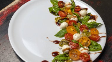 Caprese salatası. Kiraz domatesli sağlıklı yemek, mozarella topları, baharatlar, taze roket ve fesleğen. Ev yapımı, lezzetli yemekler. Sembolik görüntü. Lezzetli ve sağlıklı bir vejetaryen yemeği konsepti. Yakın plan..