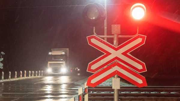 Train crossing gates closed at night. Train grade crossing with blinking or flashing lights while train is moving past. Safety concept.