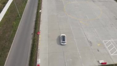Test pistinde tur atan yeni bir elektrikli arabanın havadan görüntüsü. Geniş açılı elektrikli araba test sürüşü.