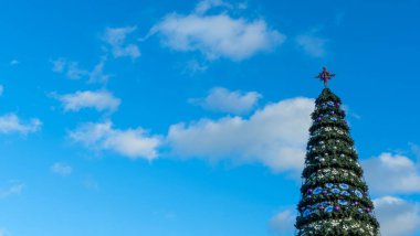 Sokakta suni bir Noel ağacındaki yıldızlar bulutlu mavi gökyüzüne karşı. Mesaj için yer var. Xmas kavramları. Şenlikli sokak dekorasyonu.