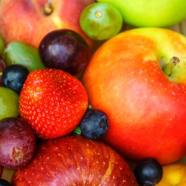 Yaz meyveleri, böğürtlen çeşitleri. Büyük elma, erik, kayısı, üzüm ve çilek. Masadaki ahşap sandıkta renkli meyveler..