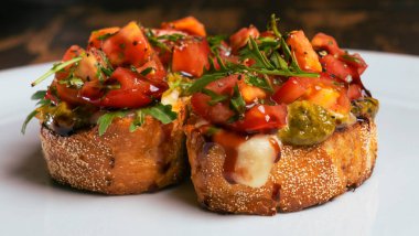 Domates ve mozzarella bruschetta 'nın yakın plan görüntüsü kırmızı tuğlalı arka planda beyaz tabakta..