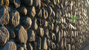 Gri ezilmiş taşlar ve güneş ışığıyla gerçek bir arka plan. Yaz günlerinde eski tuğla duvar. Soyut dekoratif arkaplan veya sanat dokusu.