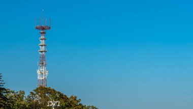 Mavi gökyüzü arka planında cep telefonu antenleri olan televizyon ve radyo kulesi..