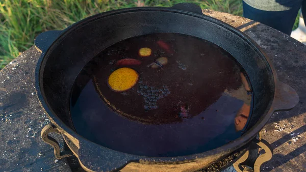 Büyük bir kazanda şarap kaynattım. Sıcak şarap büyük bir tencerede pişirilir. Geleneksel festivalde vitaminler. Çeşitli meyve ve baharatlarla sıcak şarap.