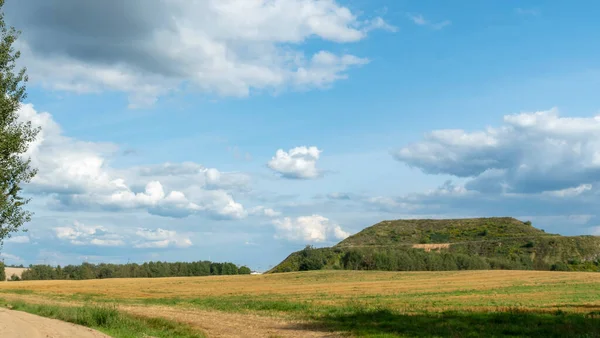 Kapalı şehir çöplüğü. Bölgenin restorasyonu. Büyük bir çöp yığınının peyzajı. Arka planda bir metropol ve bulutlu mavi bir gökyüzü var..