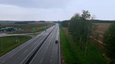 Yol ve ulaşımın havadan görüntüsü. Otoyolda arabalarla seyahat eden insanlar. Arka planda Belarus 'taki Zafer Tepesi var. Dramatik gökyüzü.