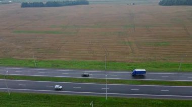 Otoyolda giden arabaların hava görüntüsü. Şehrin dışındaki yol yukarıdan panoramik görünüyor. Lojistik kavram.
