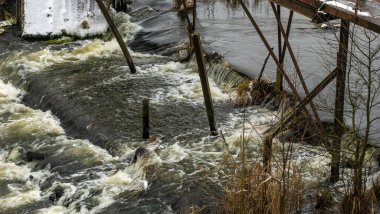 Bir yaya köprüsünün altındaki kış nehrinde kaynar su. Soyut arkaplan. Mesaj için yer var. Doğa kavramları.
