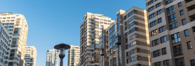 Yüksek binaların yakınındaki sıkışık avlu. Mavi gökyüzünün arka planında büyük bir apartman. Komşuluk kavramları.