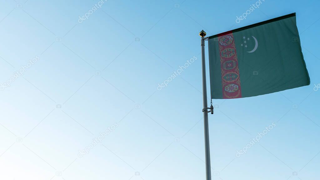 National flag of Turkmenistan on a flagpole in front of blue sky with sun rays and lens flare. Diplomacy concept. International relations. Space for text.