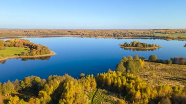 Sonbahar ormanı ve göl. Yukarıdan bak. Güneşli Sonbahar Gününde Göldeki Bir Adanın Hava Fotoğrafı. Doğa konsepti.