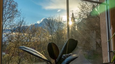 Güneş ışığı, güzel bir kadının penceresinden içeri girer. Kilisenin silueti ve arka planda bulutlu gökyüzü. Tapma kavramı.