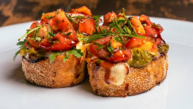Domates ve mozzarella bruschetta 'nın yakın plan görüntüsü kırmızı tuğlalı arka planda beyaz tabakta..
