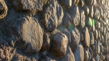 Gri ezilmiş taşlar ve güneş ışığıyla gerçek bir arka plan. Yaz günlerinde eski tuğla duvar. Soyut dekoratif arkaplan veya sanat dokusu.