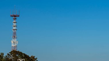 Mavi gökyüzü arka planında cep telefonu antenleri olan televizyon ve radyo kulesi..