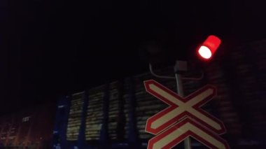 Bir halk treni gece vakti yol seviyesindeki bir geçitten geçer. Uzun yük trenleri gece demiryolunda hareket eder. Lojistik kavram.