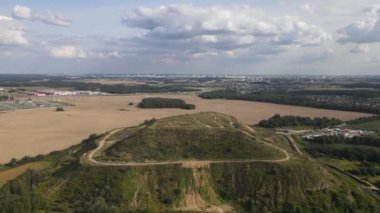 Kapalı şehir çöplüğü. Bölgenin restorasyonu. Büyük bir çöp yığınının peyzajı. Arka planda bir metropol ve bulutlu mavi bir gökyüzü var..
