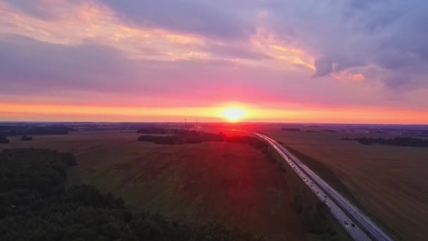 美丽的蜿蜒小路带着晚霞穿过乡村 戏剧性的天空背景 红色落日下高速公路的空中景观 交通背景 靠近农村土地的道路景观 — 图库视频影像