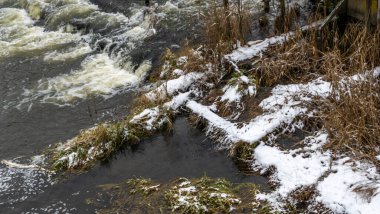 Bir yaya köprüsünün altındaki kış nehrinde kaynar su. Soyut arkaplan. Mesaj için yer var. Doğa kavramları.