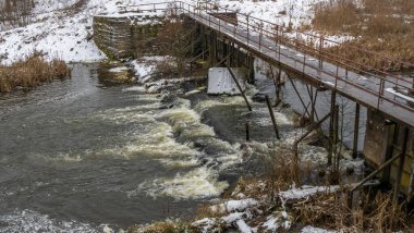 Bir yaya köprüsünün altındaki kış nehrinde kaynar su. Soyut arkaplan. Mesaj için yer var. Doğa kavramları.