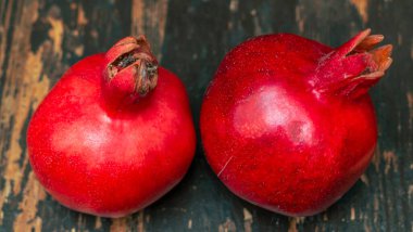 Masada iki kırmızı nar yatıyordu. Ahşap masada iki olgun taş. Tüylü yemek. Hayat konsepti.
