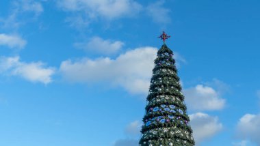 Sokakta suni bir Noel ağacındaki yıldızlar bulutlu mavi gökyüzüne karşı. Mesaj için yer var. Xmas kavramları. Şenlikli sokak dekorasyonu.
