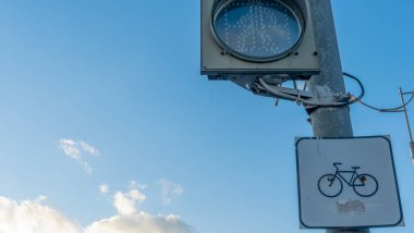 Mavi gökyüzünde, arka planda bulutlar olan trafik ışıkları üzerinde bisiklet yolu simgesi simgesi. Bisiklet yolu ile yaya geçidi. Ekolojik taşıma kavramları.