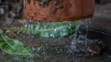 Boru hattından akan yağmur damlalarının yakın görüntüsü. Çatıdan güçlü bir su akışı bir borudan geçer. Yağmur kavramları. Tasarım için resim. Metin için boşluk.