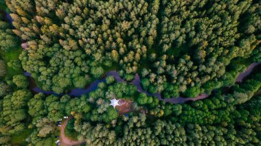Akşamları nehir kıyısındaki ağaçların arasındaki büyük çadırın hava aracı görüntüsü..