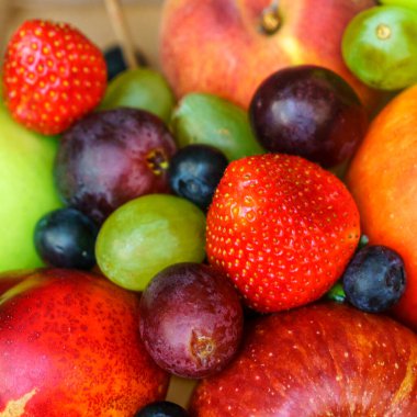 Yaz meyveleri, böğürtlen çeşitleri. Büyük elma, erik, kayısı, üzüm ve çilek. Masadaki ahşap sandıkta renkli meyveler..