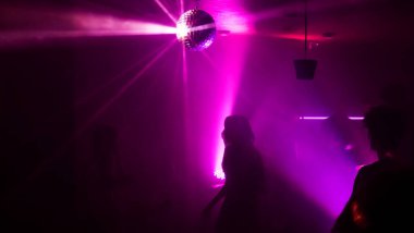 Disko gece kulübünde DJ 'in sahnede yaptığı müzikle dans eden insanların silueti. Disko topuyla parti atmosferi. Gece hayatı konsepti. Metin için boşluk.