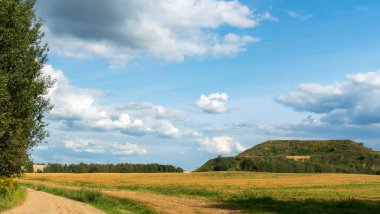 Kapalı şehir çöplüğü. Bölgenin restorasyonu. Büyük bir çöp yığınının peyzajı. Arka planda bir metropol ve bulutlu mavi bir gökyüzü var..