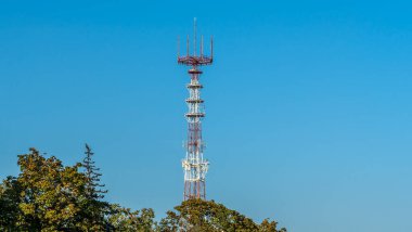 Mavi gökyüzü arka planında cep telefonu antenleri olan televizyon ve radyo kulesi..