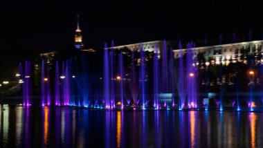 Geceleyin bir nehirde çok renkli bir müzik çeşmesi. Aydınlanmadan kaynaklanan gece çeşmesi. Mesaj için yer var. Kutlama konsepti.