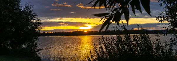 Göldeki şafak güneşinin ışınları. Nehirdeki günbatımı bulutlarının yansıması. Kırsal alan. Panoramik pankart. Doğa konsepti.