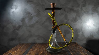 Yeni modern oryantal nargile. Gri arka plandaki ahşap masada duruyor..