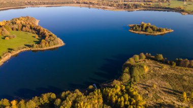 Sonbahar ormanı ve göl manzarası. Orman gölü üzerinde sonbahar güneşli bir akşam. Kırsal alan.