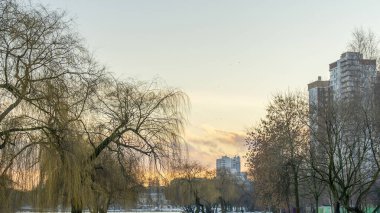 İlk kar şehirdeki yerleşim yerlerini kaplıyor. Güneş ışığı ve bulutlu gökyüzü. Şehir kavramları. Arka planda yüksek binalar var..